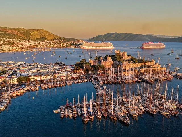 Luftaufnahme bei Sonnenuntergang von der Burg von Bodrum, dem Yachthafen und Kreuzfahrtschiffen in der Ferne