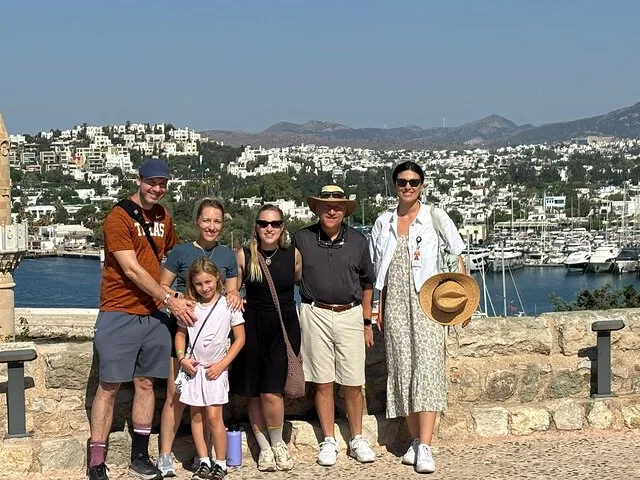 Sechsköpfige Familie im Freien mit Blick auf den Yachthafen von Bodrum und weiße Häuser