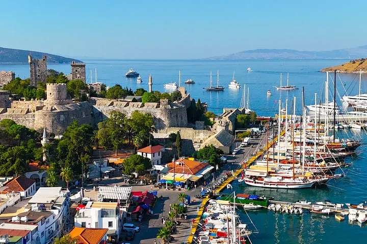 Blick von oben auf die Burg von Bodrum und den belebten Yachthafen mit traditionellen Gulet-Booten