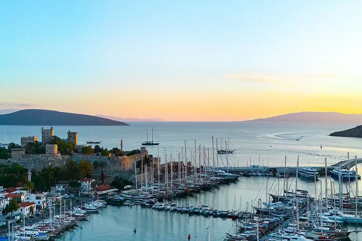 Sunset view of Bodrum Castle and the marina with boats and distant hills